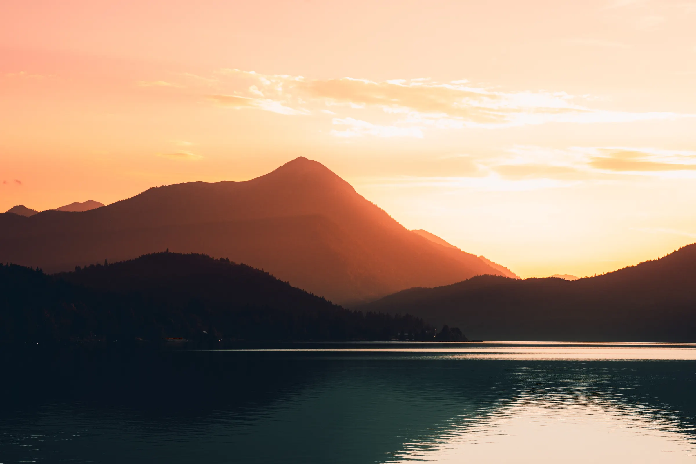 Sonnenuntergang am Kochelsee mit ruhigem Wasser und Bergsilhouette